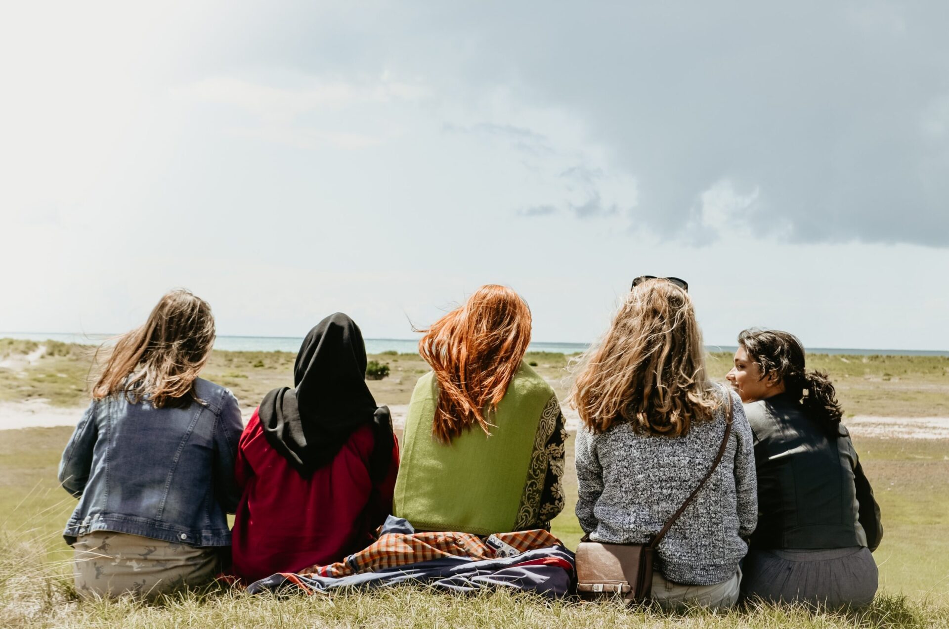 5 girls/woman sat looking out over the ocean